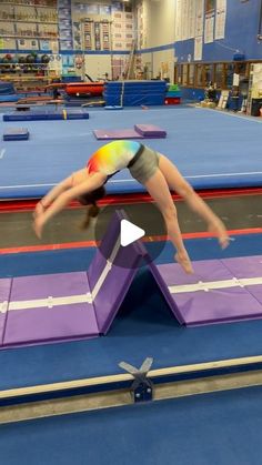 a person doing a handstand on top of a purple and blue trampoline