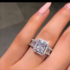 a woman's hand with two engagement rings on it and the ring is surrounded by diamonds