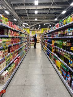 an aisle in a grocery store filled with lots of food and drink bottles on the shelves