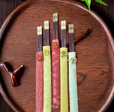 three different colored chopsticks sitting on top of a wooden plate