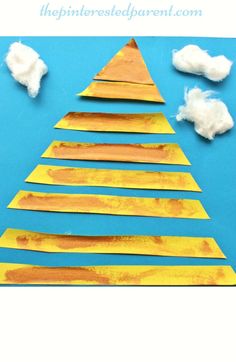 a paper plate christmas tree made out of construction paper and clouds on a blue background