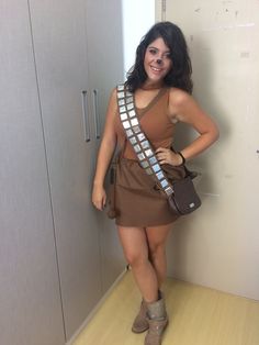 a woman in a brown dress is holding a purse and posing for the camera with her hands on her hips