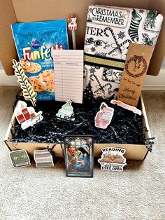 an open box filled with assorted items on top of a carpeted floor next to a wall