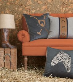 an orange couch sitting next to a lamp on top of a wooden box filled with hay