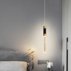 a bedroom with a bed, night stand and lamp hanging from the ceiling above it