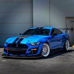 a blue sports car parked in front of a garage