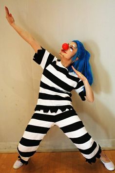 a woman with blue hair and clown makeup is dressed in black and white striped clothing