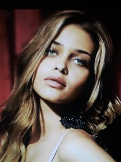 a close up of a person wearing a bra and posing for a photo in front of a red curtain