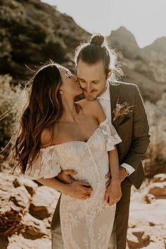 a bride and groom kissing in the desert