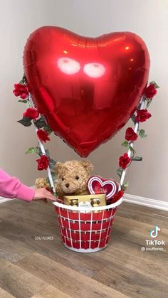 a teddy bear in a basket with a heart balloon