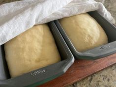 two loafs of bread sitting in pans on top of a counter