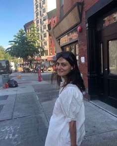 a woman is standing on the sidewalk waving