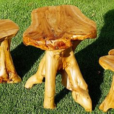 three wooden tables and two stools sitting in the grass