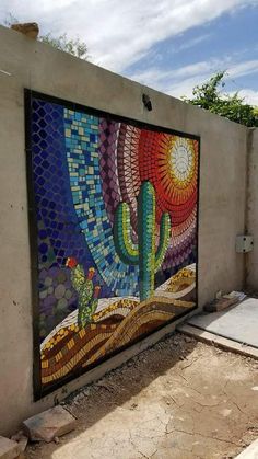 a colorful mosaic on the side of a building with cactus and sun in it's center