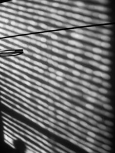 black and white photograph of the side of a building with sunlight coming through blinds on it