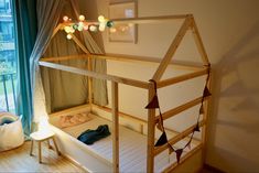 a wooden bunk bed sitting in a bedroom next to a window with curtains on it