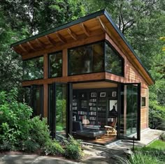 a small house with lots of windows in the front and side of it, surrounded by trees