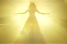 a woman standing in the light with her arms outstretched