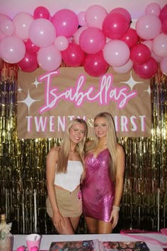 two beautiful young women standing next to each other in front of balloons and streamers