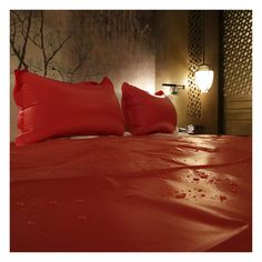 a bed with red sheets and pillows on it