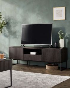 a flat screen tv sitting on top of a wooden entertainment center in a living room