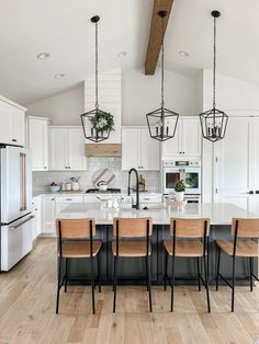 a large kitchen with white cabinets and wooden flooring, along with an island in the middle