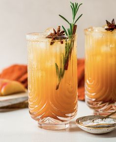 two glasses filled with drinks sitting on top of a white table next to plates and utensils