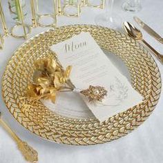 a table setting with gold place settings and silverware, including a menu on a plate