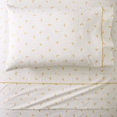 a bed with white sheets and yellow polka dots on the pillowcase, along with two pillows