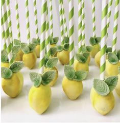 there are many lemons with green leaves on them and straws in the shape of apples