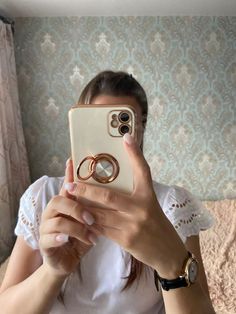 a woman taking a selfie with her cell phone and two wedding rings on it