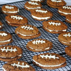 cookies with white frosting and footballs are on a cooling rack, ready to be eaten