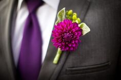 a man wearing a suit and tie with a purple flower in his lapel pin