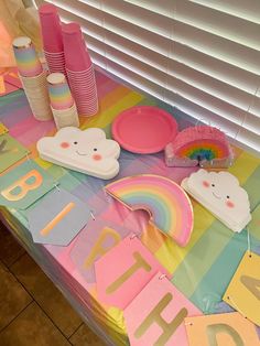 a table topped with lots of colorful paper plates and cupcakes on top of it