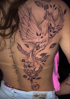 a woman's back with a bird tattoo on it