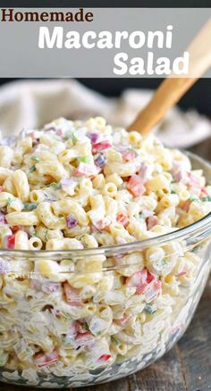 a glass bowl filled with macaroni salad on top of a wooden cutting board