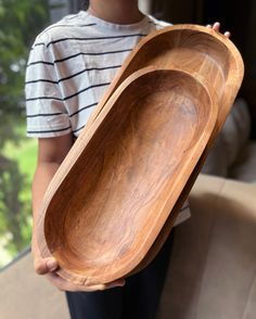 a person holding two wooden trays in their hands