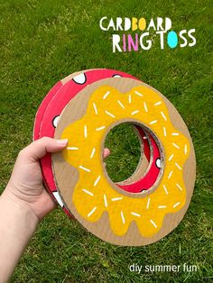 someone is holding up a cardboard doughnut ring tosser on the grass with their hand