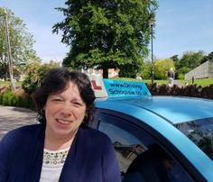 a woman standing in front of a blue car