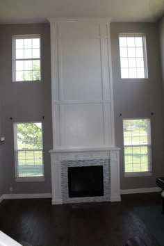 an empty living room with three windows and a fireplace in the middle of the room