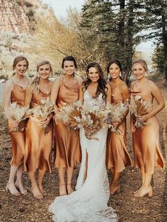 a group of women standing next to each other in front of trees and bushes with flowers