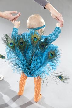 a baby dressed up like a peacock with feathers