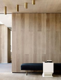 a room with wood paneling and black couch next to it on a hard wood floor