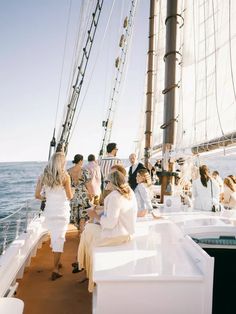 people are sitting on the deck of a sailboat