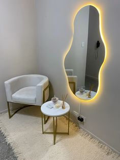 a white chair sitting next to a round mirror on a wall above a small table