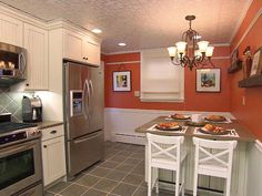 a kitchen with white cabinets and stainless steel appliances is pictured in this image, there are three chairs at the center of the table