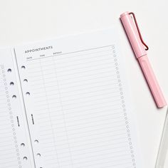 a pink pen sitting on top of a white table next to a notepad with appointments