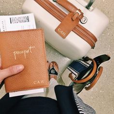 a person is holding a passport in front of two suitcases and a handbag