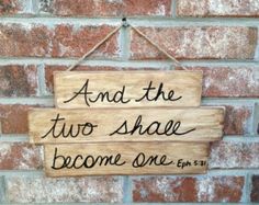 a wooden sign hanging on the side of a brick wall that says and the two shall become one