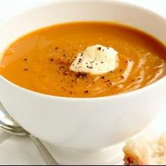 a white bowl filled with soup next to a piece of bread